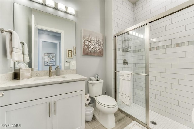 full bathroom with a stall shower, vanity, and toilet