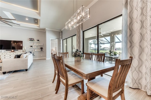 dining space featuring crown molding, light wood finished floors, a high ceiling, a ceiling fan, and baseboards