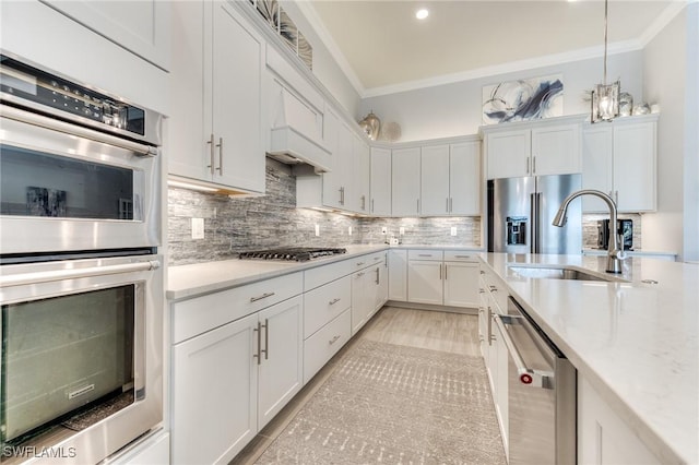 kitchen featuring appliances with stainless steel finishes, crown molding, a sink, and white cabinetry