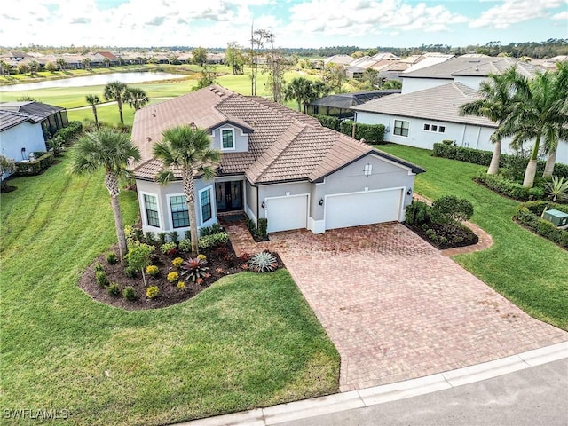 mediterranean / spanish home with a tile roof, an attached garage, decorative driveway, a front yard, and stucco siding