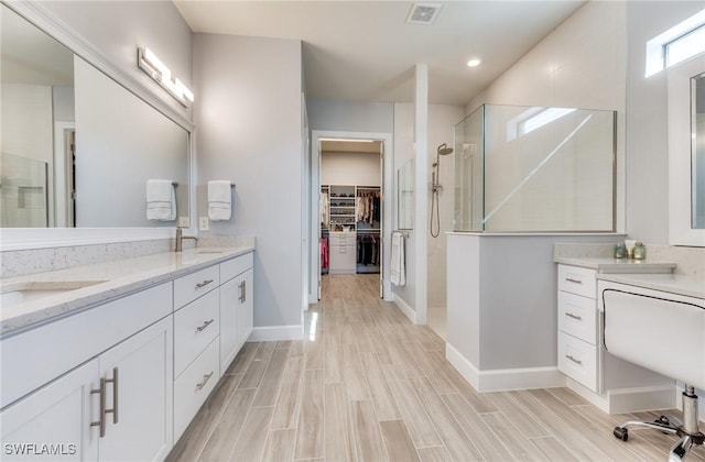 bathroom with a walk in shower, wood finish floors, a sink, and visible vents