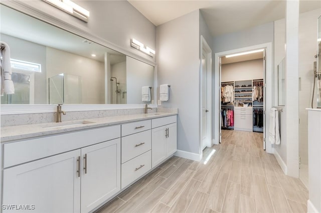 full bathroom with double vanity, walk in shower, a sink, and a walk in closet