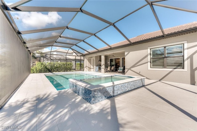 view of swimming pool featuring a patio area, a pool with connected hot tub, glass enclosure, and a ceiling fan