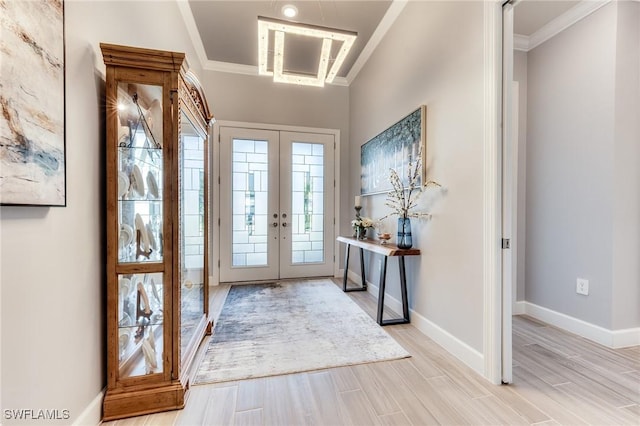 foyer entrance with french doors, crown molding, light wood-style flooring, and baseboards