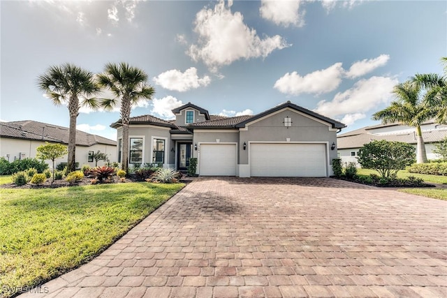 mediterranean / spanish house with a garage, decorative driveway, a front yard, and stucco siding