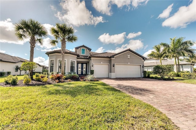 mediterranean / spanish home featuring decorative driveway, a tile roof, stucco siding, an attached garage, and a front lawn