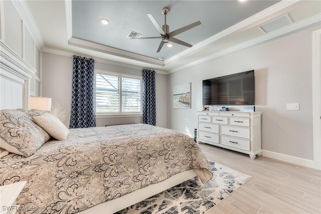 bedroom featuring crown molding, light wood finished floors, a raised ceiling, visible vents, and baseboards