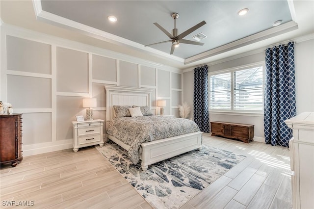 bedroom featuring visible vents, a tray ceiling, and a decorative wall