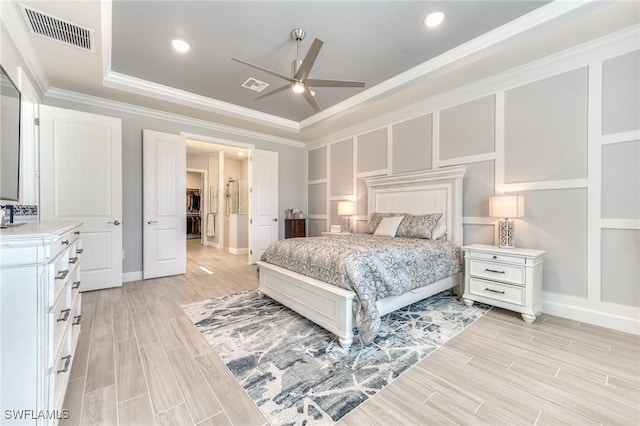 bedroom featuring a tray ceiling, wood finish floors, visible vents, and crown molding