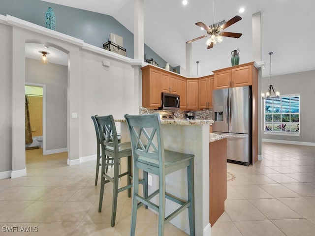 kitchen featuring light tile patterned floors, tasteful backsplash, light stone counters, a breakfast bar area, and stainless steel appliances