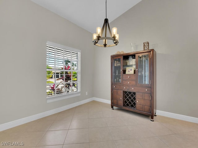 unfurnished dining area featuring light tile patterned floors, baseboards, a chandelier, and high vaulted ceiling