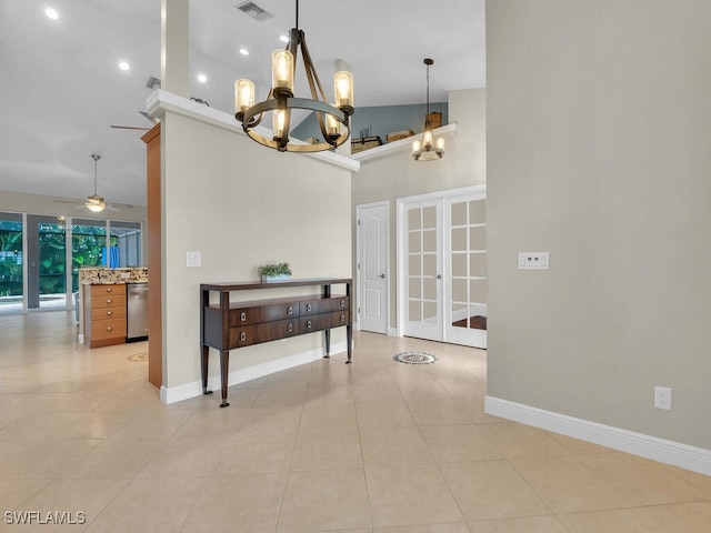 interior space with light tile patterned floors, a towering ceiling, baseboards, visible vents, and an inviting chandelier