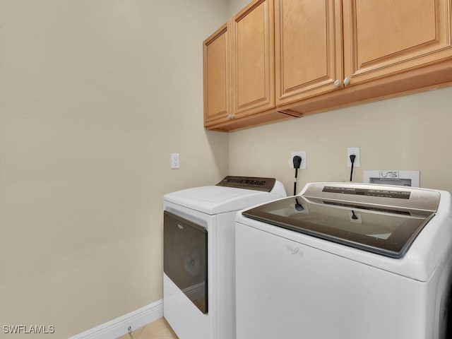 laundry room featuring cabinet space, light tile patterned floors, baseboards, and washer and dryer