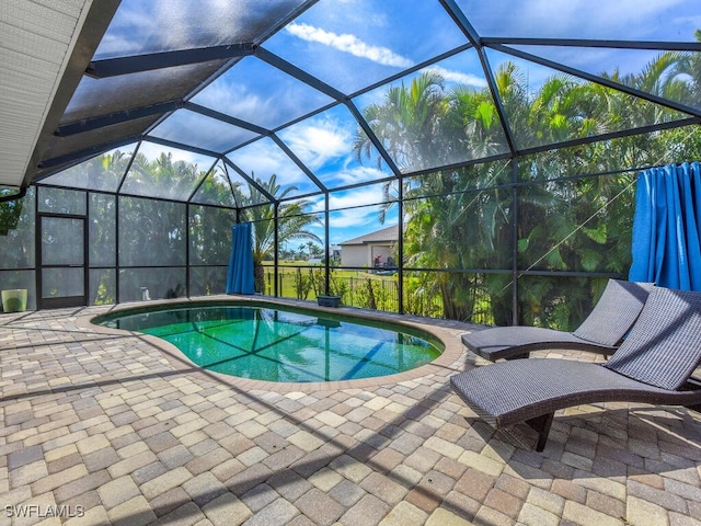 pool featuring glass enclosure and a patio