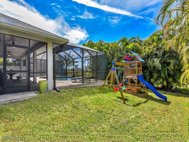 view of playground with glass enclosure, an outdoor pool, a lawn, and a patio