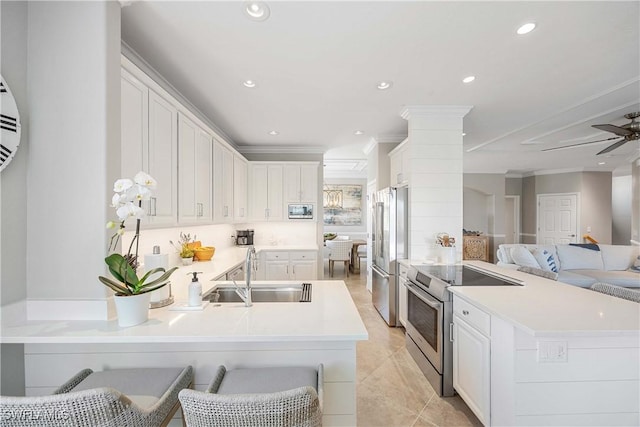 kitchen featuring stainless steel appliances, a peninsula, a sink, open floor plan, and ornamental molding