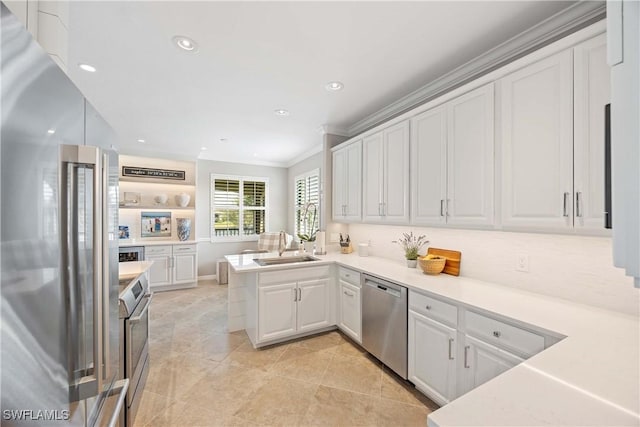 kitchen with stainless steel appliances, light countertops, white cabinetry, a sink, and a peninsula