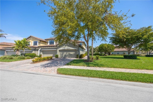 view of front of home with decorative driveway, stucco siding, an attached garage, a front yard, and a tiled roof