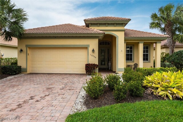 12020 Bramble Cove Dr, Fort Myers, FL 33905 - mediterranean / spanish-style house featuring stucco siding, an attached garage, a tile roof, and decorative driveway