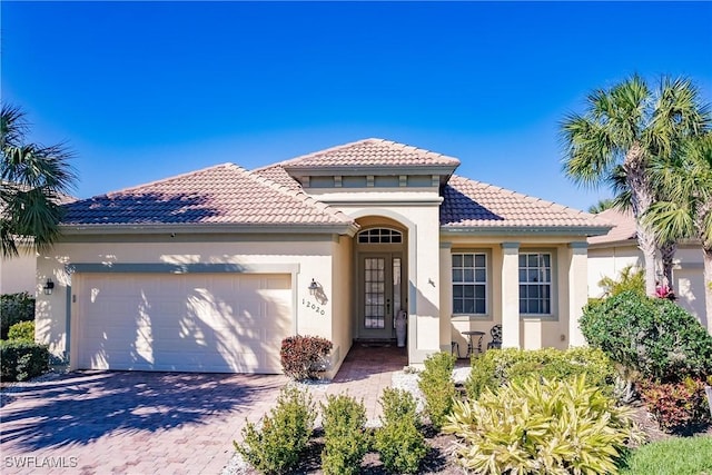 12020 Bramble Cove Dr, Fort Myers, FL 33905 - mediterranean / spanish house with decorative driveway, a tile roof, stucco siding, and a garage