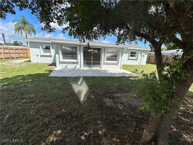 rear view of property with a yard, a patio area, fence, and stucco siding