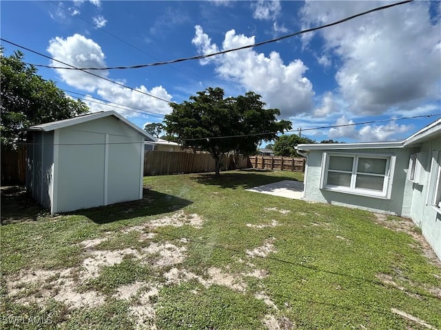 view of yard with a patio area, a fenced backyard, a storage shed, and an outbuilding