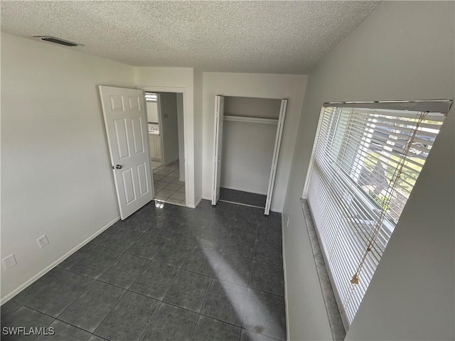 unfurnished bedroom featuring a closet, visible vents, a textured ceiling, and baseboards