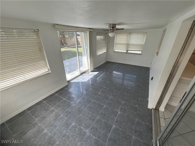 unfurnished room featuring ceiling fan, dark tile patterned floors, and baseboards