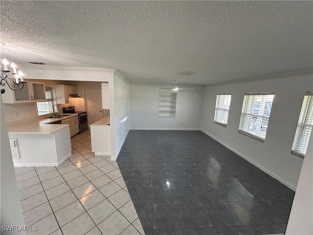 unfurnished living room with crown molding, light tile patterned floors, a textured ceiling, baseboards, and ceiling fan with notable chandelier