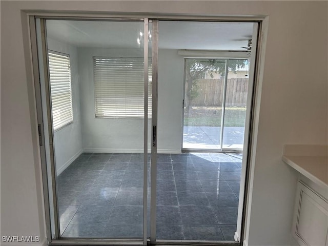 doorway featuring ceiling fan, baseboards, and tile patterned floors