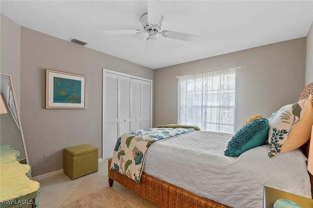 bedroom featuring light tile patterned floors, visible vents, baseboards, a ceiling fan, and a closet