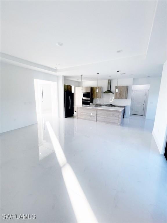 kitchen with stainless steel appliances, light countertops, a large island, wall chimney exhaust hood, and modern cabinets