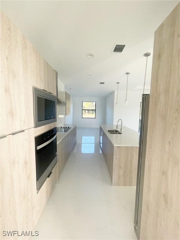 kitchen featuring light brown cabinets, modern cabinets, a sink, and oven