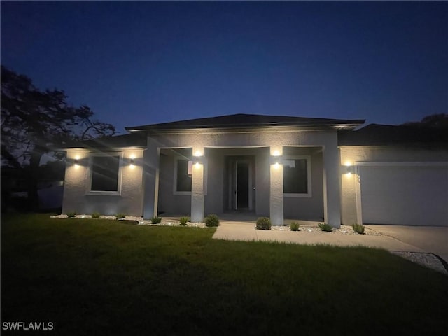 view of front of property featuring a garage, concrete driveway, a lawn, and stucco siding