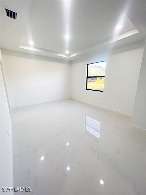 empty room with baseboards, a tray ceiling, visible vents, and recessed lighting