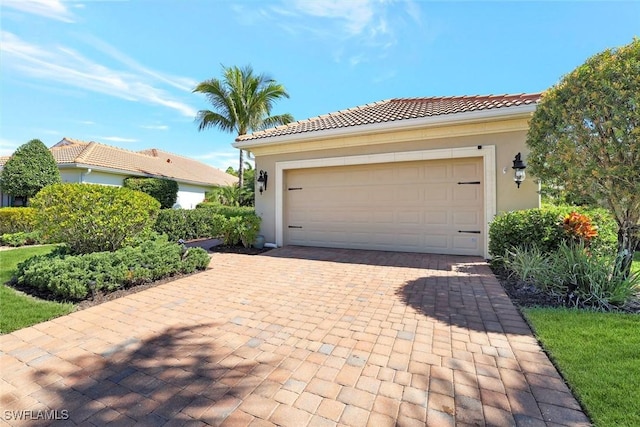 view of front of house featuring decorative driveway, a tile roof, and stucco siding