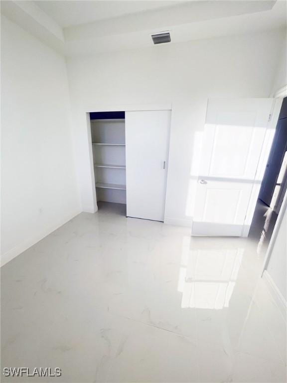 unfurnished bedroom with marble finish floor, visible vents, and a closet