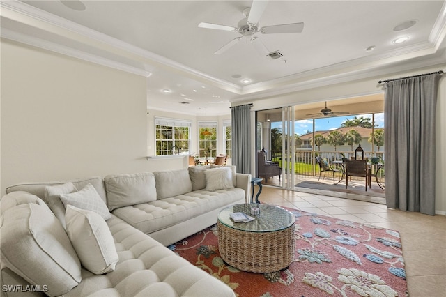 living room with plenty of natural light, a raised ceiling, crown molding, and tile patterned floors