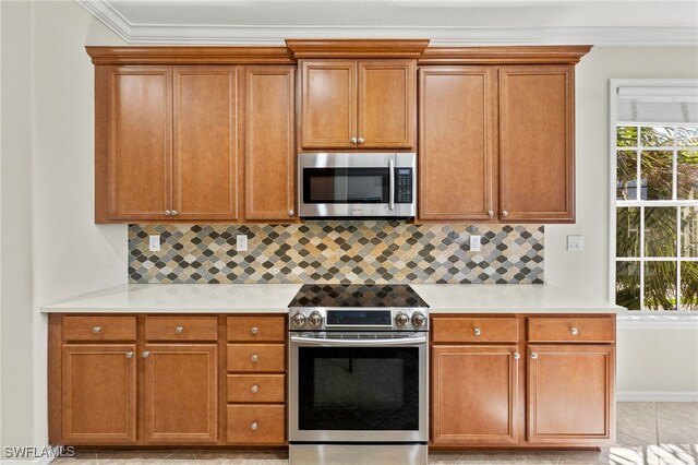 kitchen with appliances with stainless steel finishes, brown cabinetry, light countertops, and backsplash