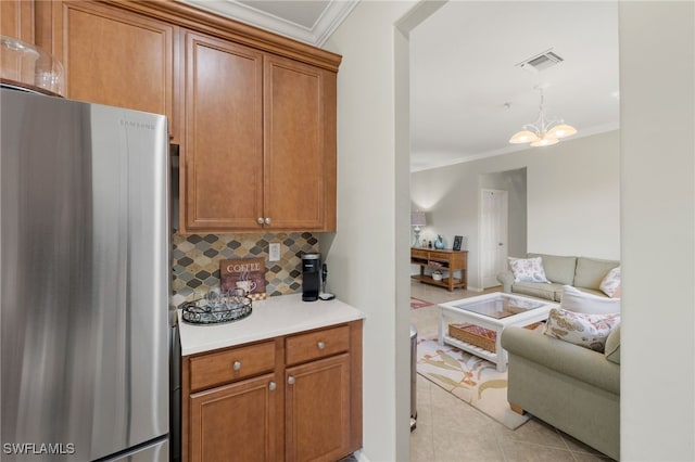 kitchen featuring brown cabinetry, tasteful backsplash, ornamental molding, and freestanding refrigerator