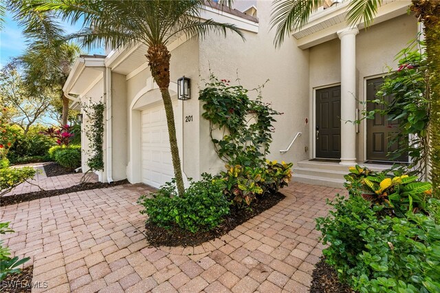 view of exterior entry featuring a garage and stucco siding