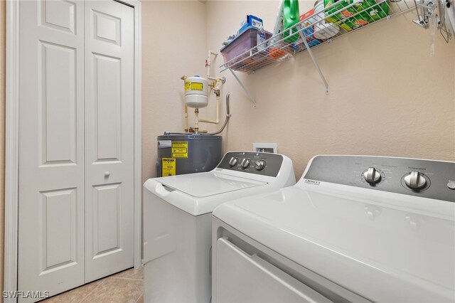 laundry area featuring laundry area, light tile patterned floors, water heater, and separate washer and dryer