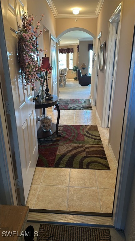 interior space featuring arched walkways, ornamental molding, and light tile patterned floors