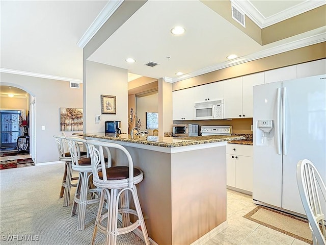 8096 Queen Palm Ln Unit 227, Fort Myers, FL 33966 - kitchen featuring a kitchen bar, visible vents, dark stone counters, white appliances, and arched walkways