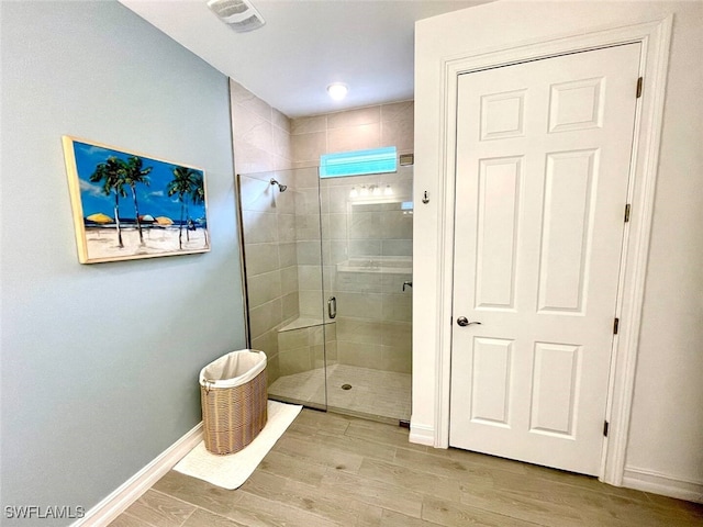 bathroom featuring visible vents, a shower stall, baseboards, and wood finished floors