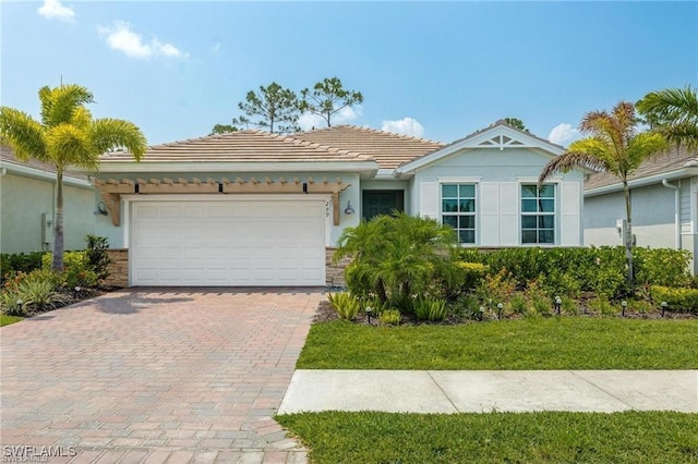 ranch-style home with stone siding, decorative driveway, a tile roof, and an attached garage