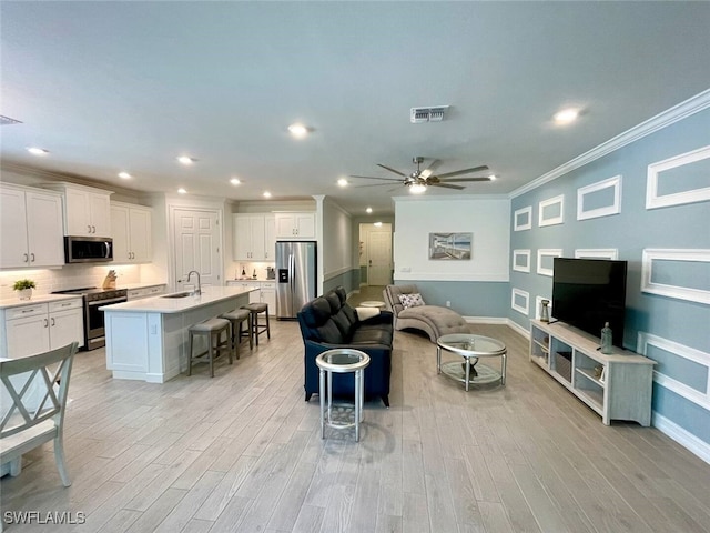 living area featuring light wood finished floors, recessed lighting, visible vents, ornamental molding, and a ceiling fan