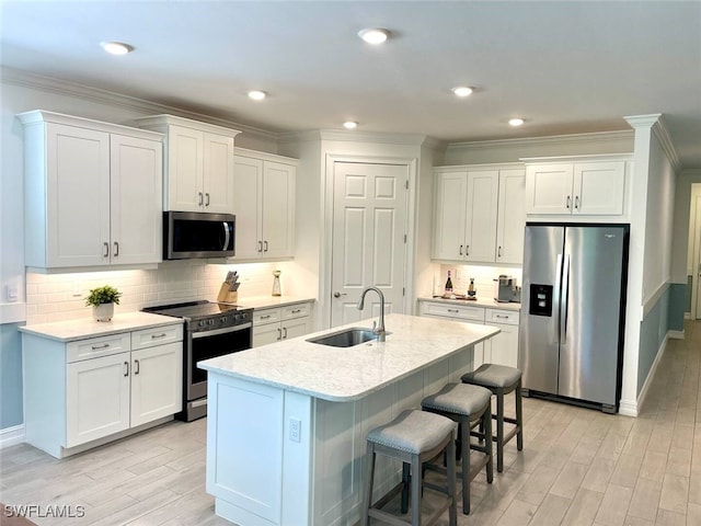 kitchen featuring crown molding, white cabinetry, stainless steel appliances, and a sink