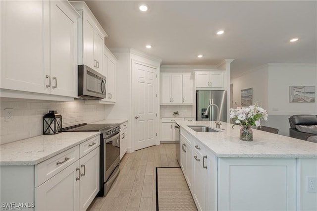 kitchen with a kitchen island with sink, appliances with stainless steel finishes, white cabinets, and a sink