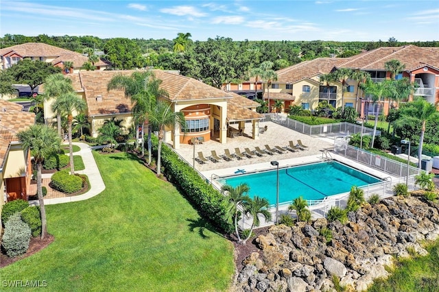 pool with a patio area, fence, and a yard